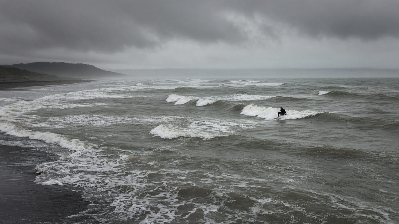 Small messy waves on a cold Southland beach, one surfer in a winter wetsuit